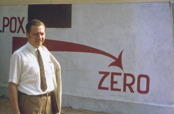 This historic image, from 1974, depicted Dr. Donald A. Henderson, standing in front of a “Smallpox Zero” sign, which was outside the Bangladesh National Smallpox Eradication Program Center, located in the country's capital city of Dhaka. During the 1960s and 70s, Dr. Henderson headed the international effort to eradicate smallpox, and to achieve the “Smallpox Zero” status for all countries throughout the World, a goal which was successfully reached. Image/CDC