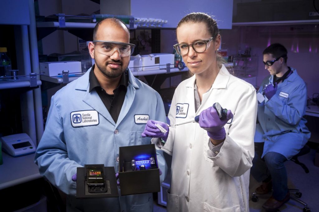 Sandia National Laboratories chemical engineer and lead paper author Aashish Priye offers a view into the Zika box prototype, along with co-authors Sara Bird, a virologist, center, and , a biomedical engineer. Photo by Randy Wong